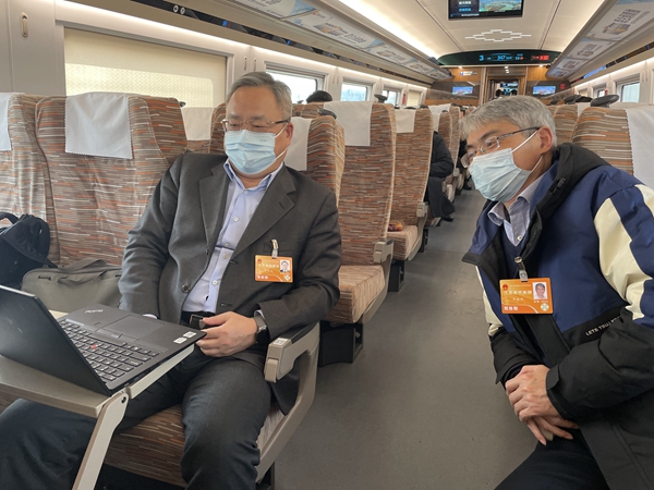 3月3日，赴京参会途中，全国人大代表佘才高、李鸿彬在交流建议修改情况。鹿伟 摄