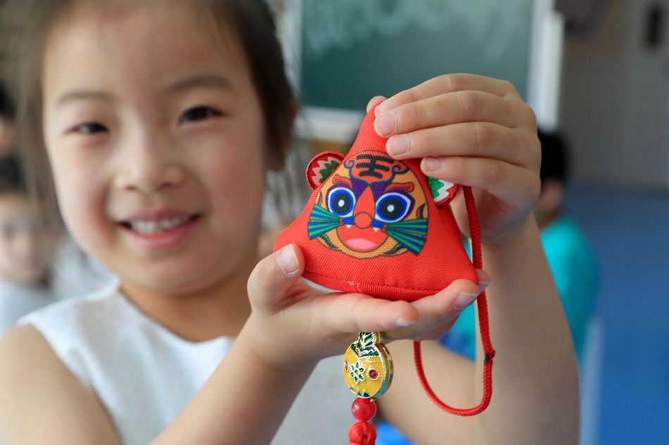 赣榆区早教中心里，孩子展示新做的荷包。邵世新摄