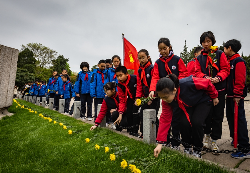参加祭扫仪式的学生向烈士墓献花。胡潇摄 