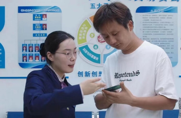 南京市民杨先生从供电营业厅工作人员手中接过为家人定制的盲文电费卡。国网江苏电力供图