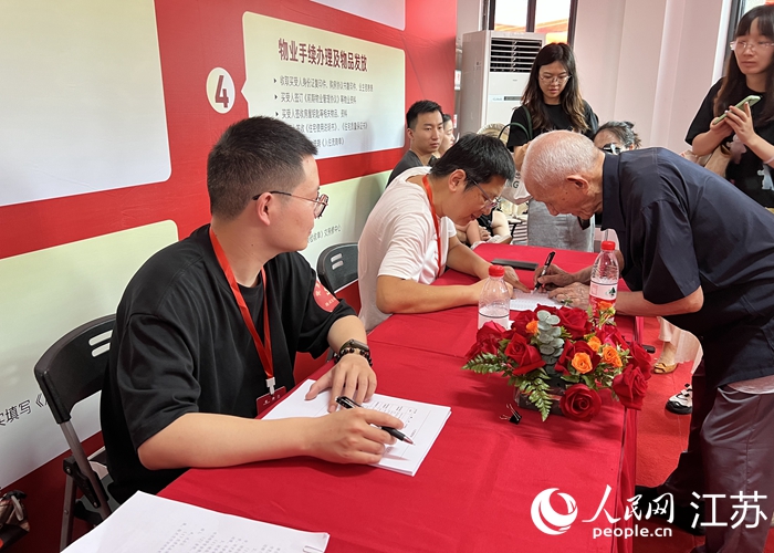 在收房现场办理手续的徐益道（右）。人民网记者 马晓波摄