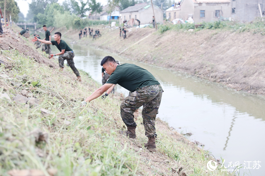 武警官兵帮助百姓清理河堤。人民网 余乐摄