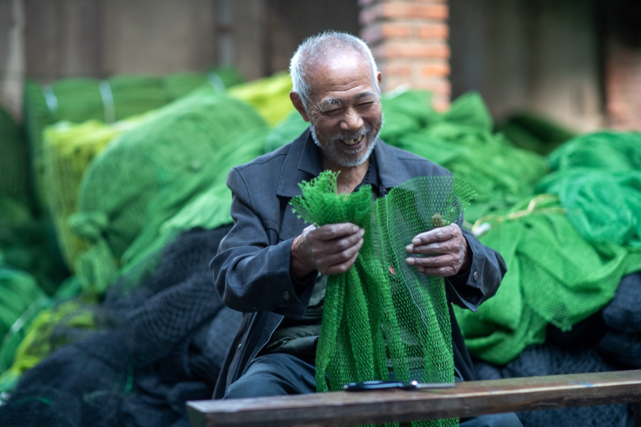 戴家村渔网编织生产基地内村民在手工编织渔网。周社根摄