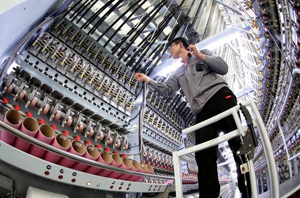 江苏沭阳县经开区智能针织产业园的一家纺织企业，工人正在操作倍捻机，绞合纱线。丁华明摄