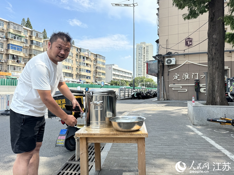 爱心茶摊前，外卖小哥陈俊兵正在接水。人民网记者 马晓波摄