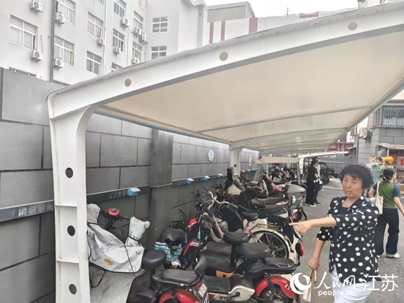 王立华为记者展示小区内新增的车棚和充电桩。