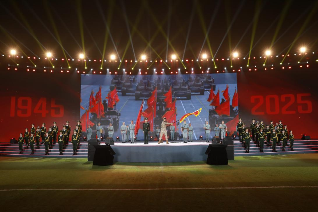 节目《战旗美如画》现场图，九三阅兵陆军方队刘老庄籍参阅战士严鹏飞现场讲述，九三阅兵战旗方队"刘老庄连"战旗擎旗手、刘老庄连现任副连长王宸一挥旗 。主办方供图