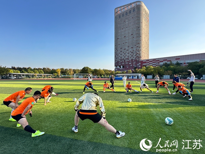 混编友谊赛前，“苏超”南京队球员与媒体人进行热身。人民网 王纯摄