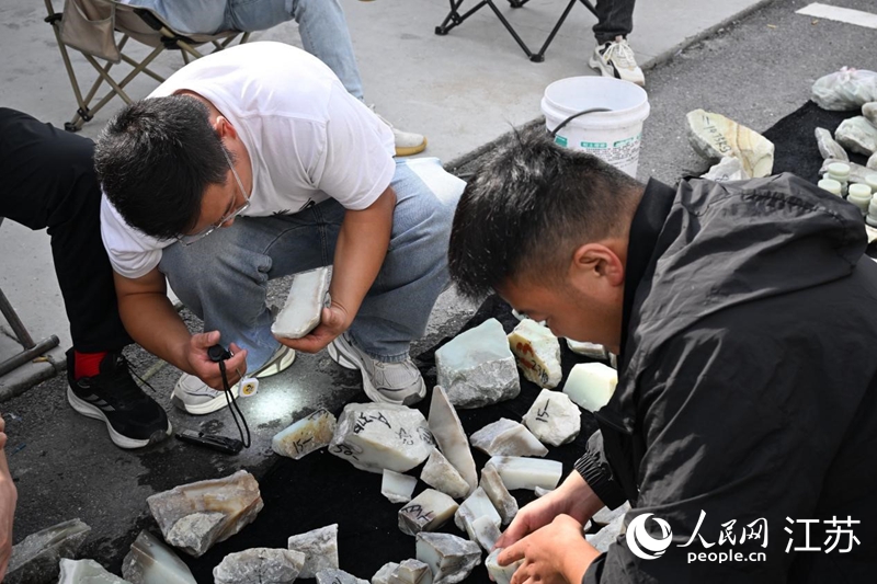 玉石原石交易区,玉石买家正在查看玉石质量。人民网记者张瀚天摄