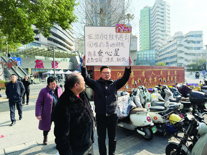 柴伟在医院门口举牌宣传爱心屋
