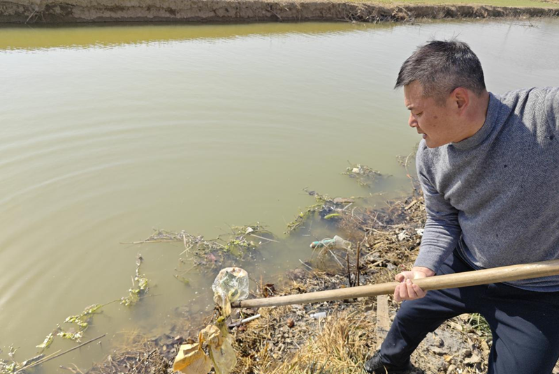 蒋恒山清理河道中的垃圾。陈允高摄