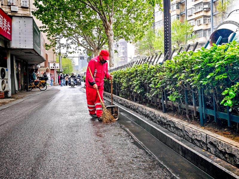 环卫工清扫路面积絮。南京城管供图