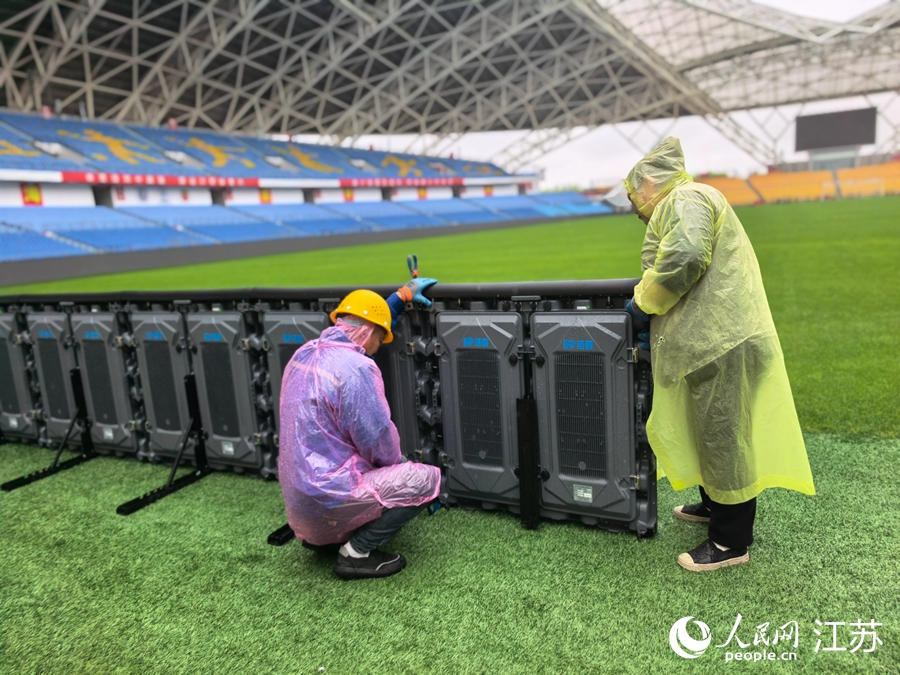 工作人员冒雨安装比赛设施。人民网记者 王继亮摄