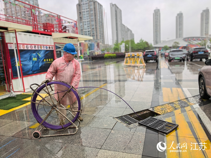 工作人员冒雨铺设电源线路。人民网记者 王继亮摄