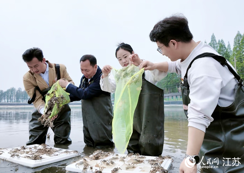 同学们在全国人大代表邢青松指导下体验蟹苗投放。人民网 崔小倩摄