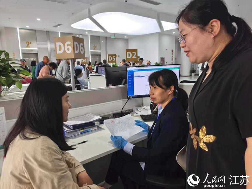 海安市人社局副局长施佳男（右）协助企业办事员办理参保手续。人民网记者 王继亮摄