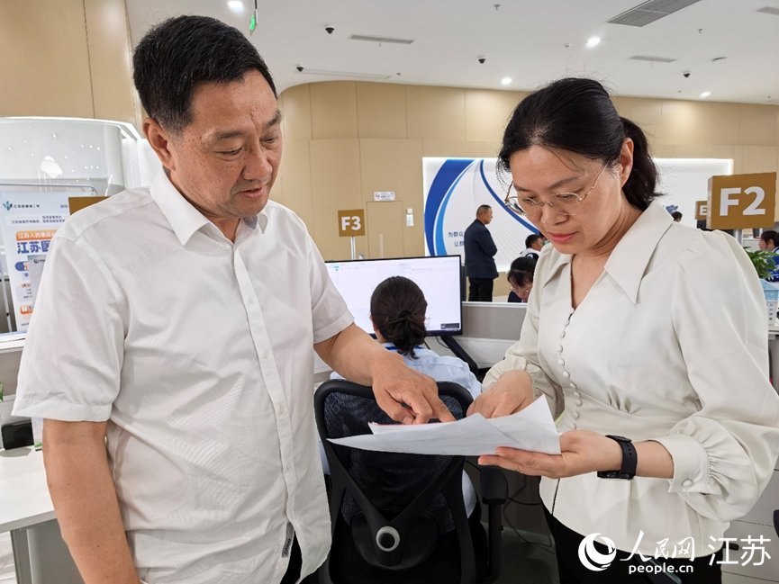 海安市医保局副局长陆晓静（右）协助群众办理医保报销。人民网记者 王继亮摄