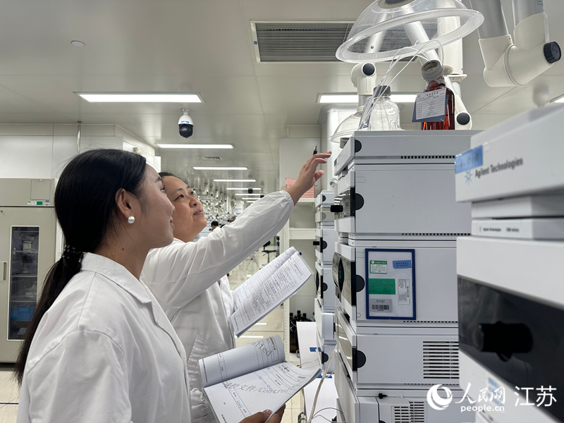 扬子江药业集团质检实验室里，胡婷婷跟同事查看仪器分析数据。人民网 赵登岩摄