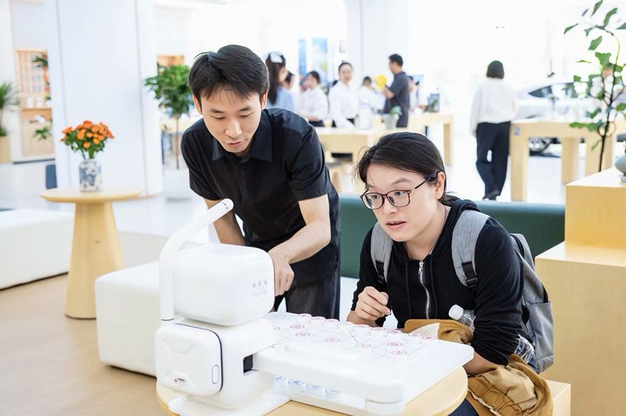 市民走进泰州移动服务厅内的数智体验区与 AI 下棋机器人人机对弈。江苏移动供图